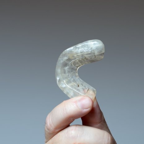Patient holding a custom nightguard for teeth grinding
